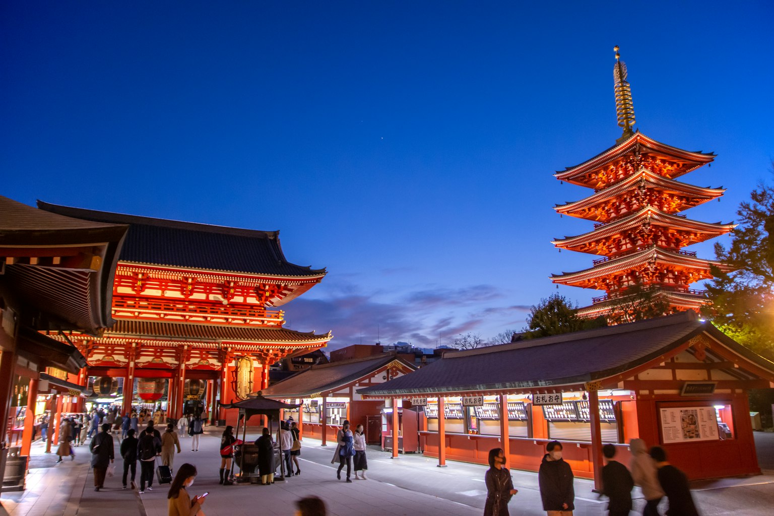 Pemandangan ramai di Kuil Senso-ji dengan pagoda di latar belakang saat senja