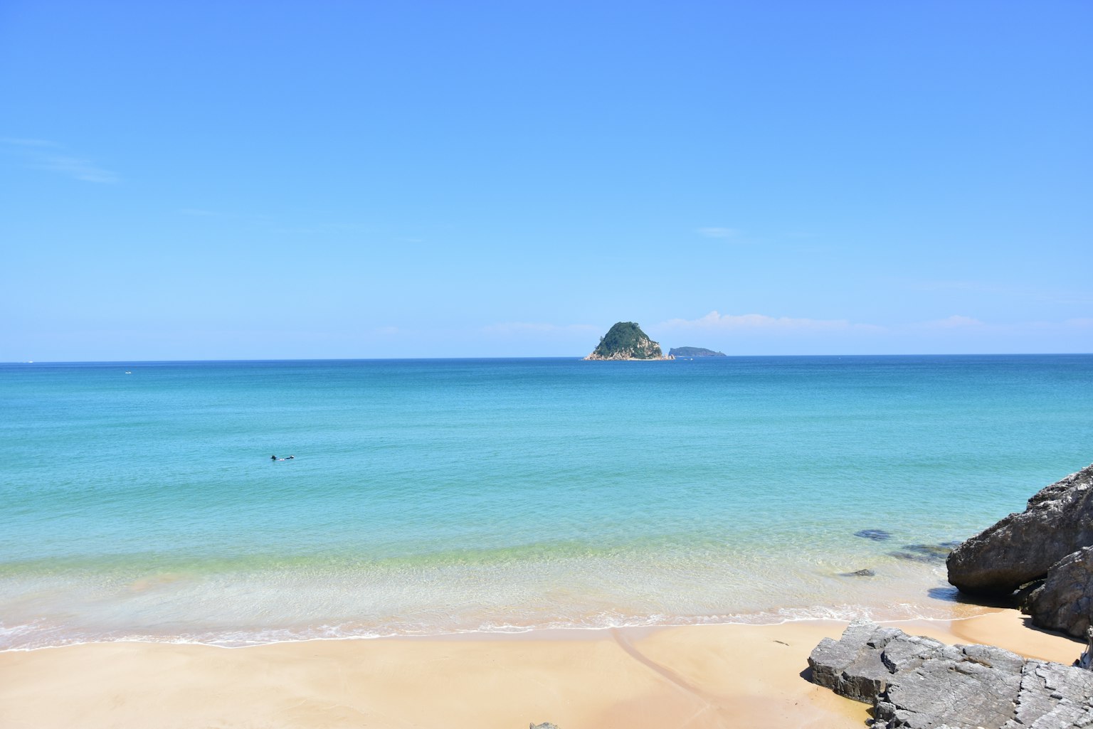 Vista de playa escénica con mar y cielo azules pequeña isla visible a lo lejos