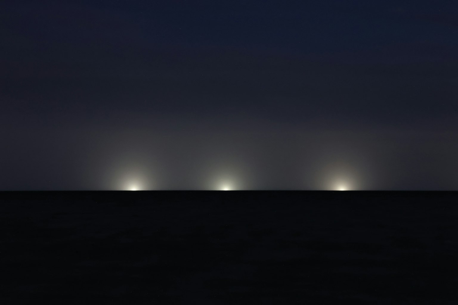 Paesaggio con tre fonti luminose brillanti su uno sfondo scuro