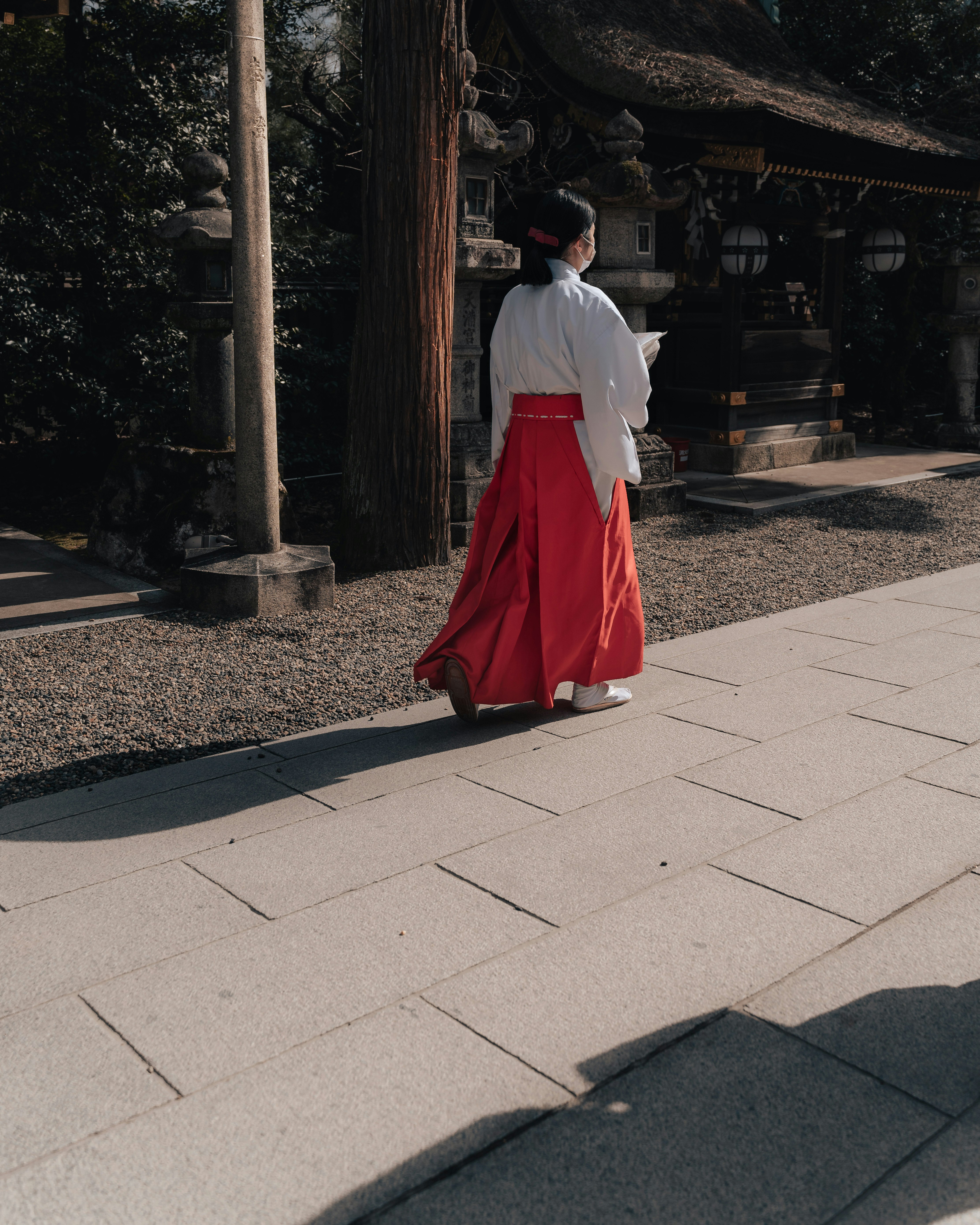 神社の参道で赤い袴をまとった女性の後ろ姿