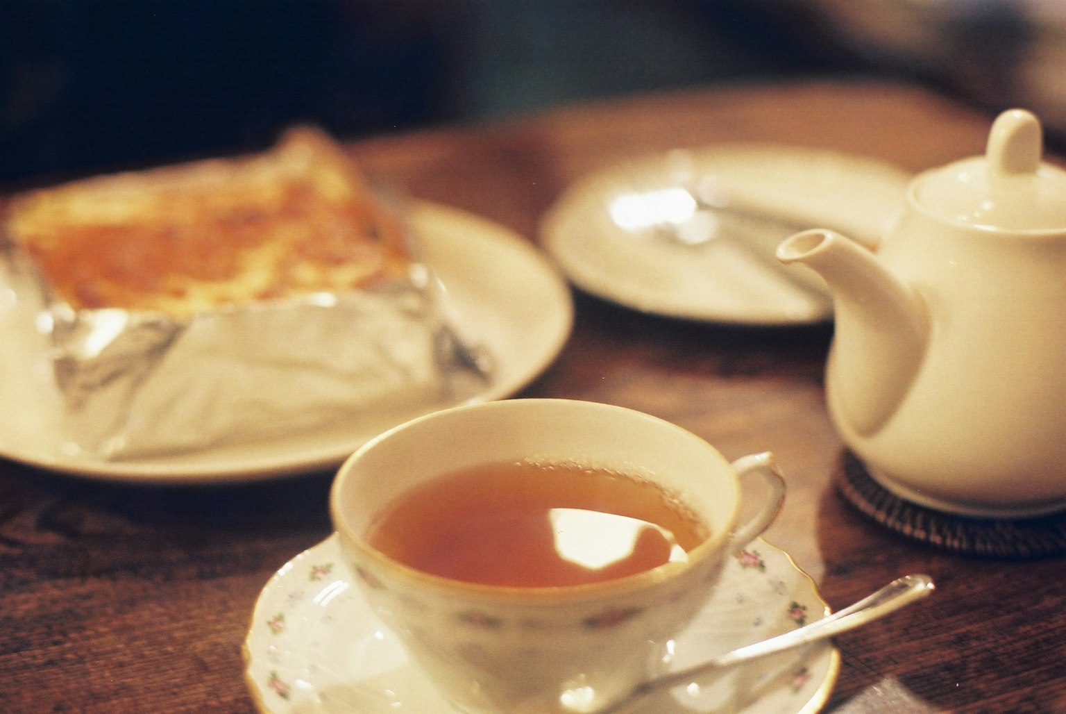 桌面場景有茶杯和茶壺旁邊放著烘焙食品