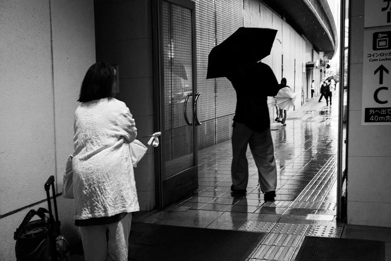雨の中で傘を持つ男性と女性が対面するシーン