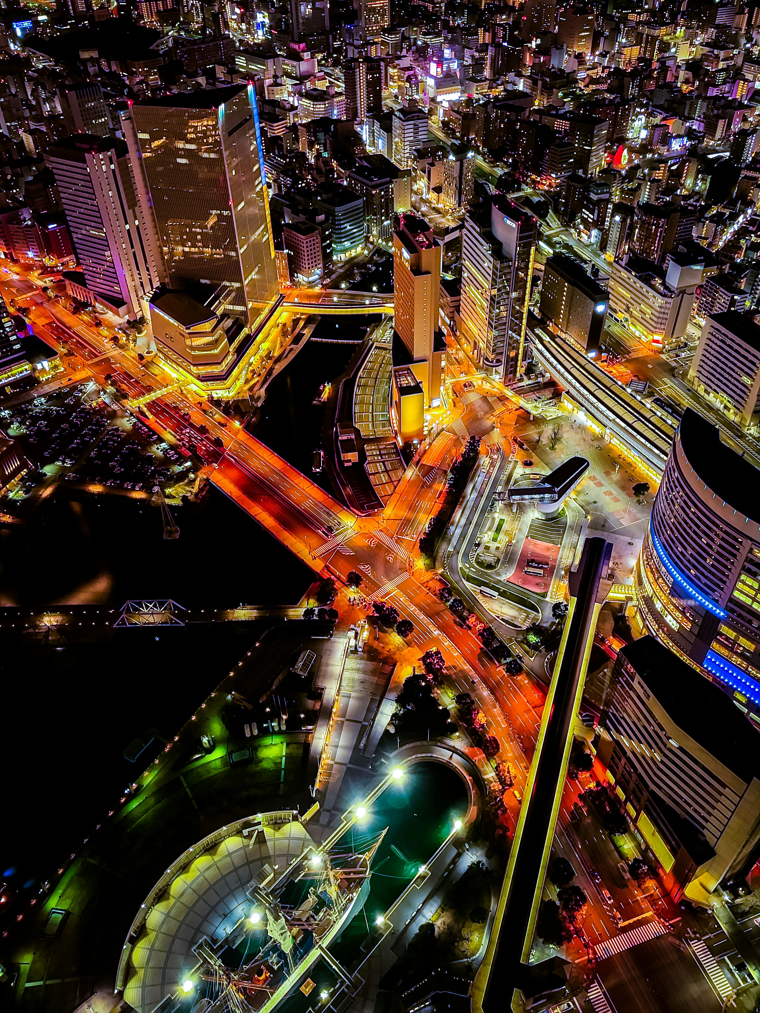 ネオン輝く高層ビルと交差する大通りの夜景
