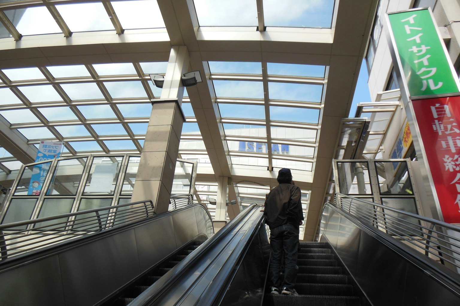 Una persona che sale una scala mobile all'aperto con vista sul cielo blu e architettura moderna