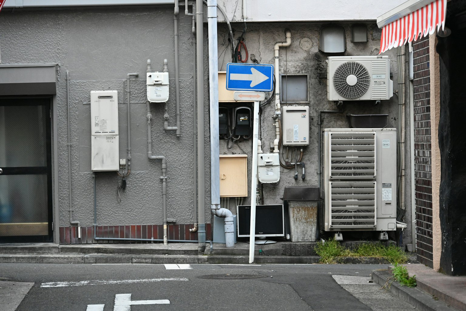 Esquina de la calle con pared gris y medidores eléctricos y unidades de aire acondicionado