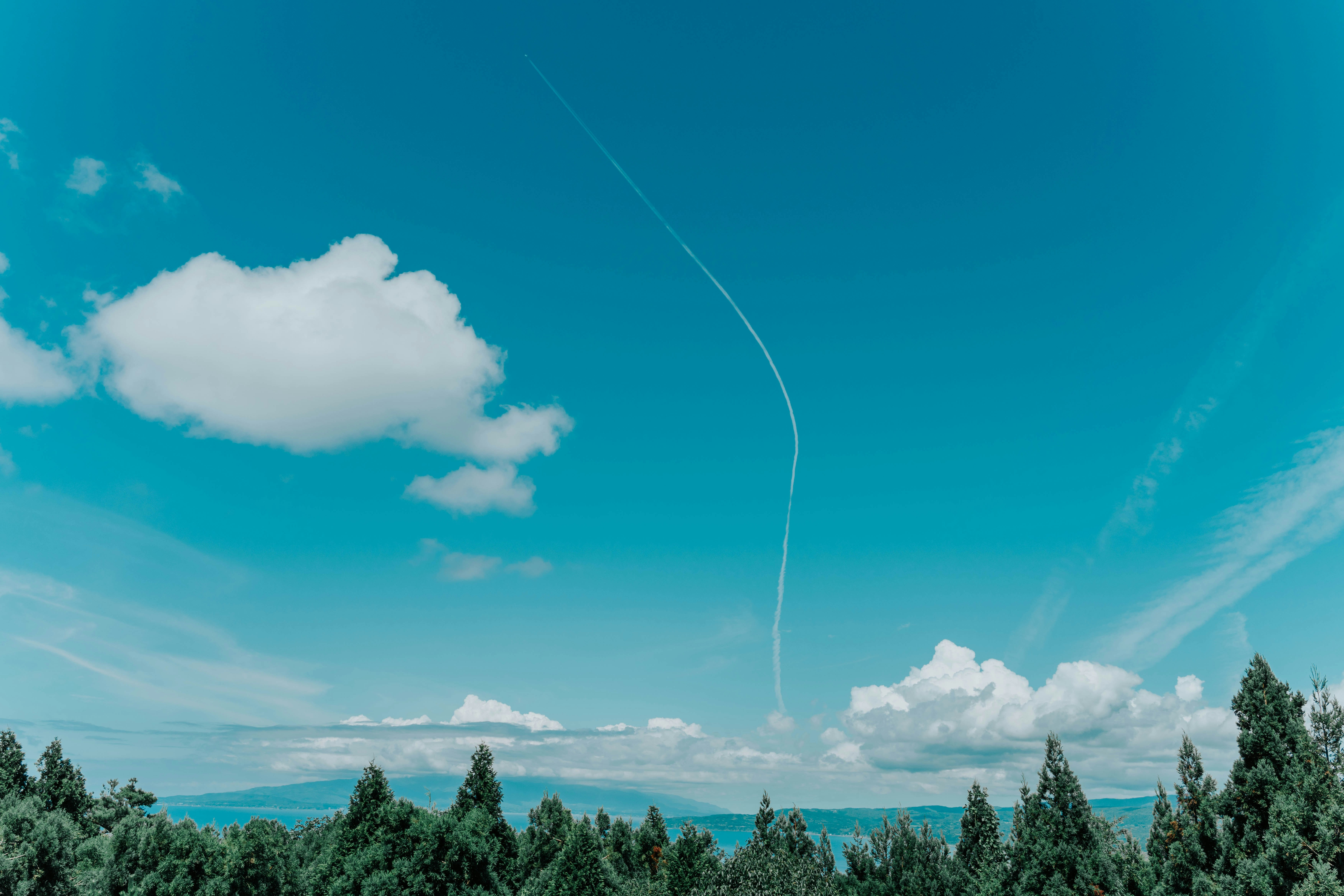 Scenic view of blue sky with white clouds and a contrail