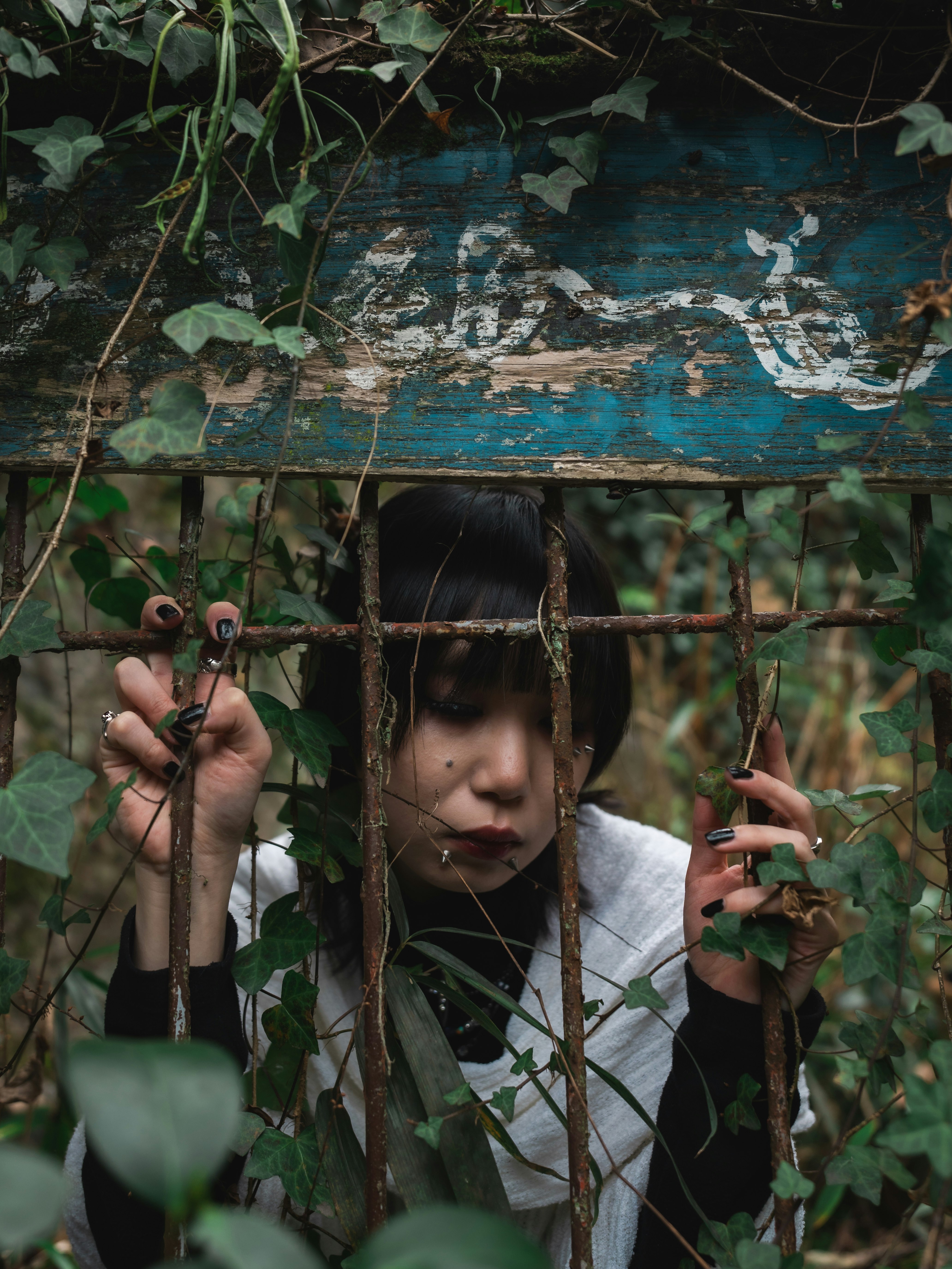 茂みの中で竹の柵越しに見つめる子ども