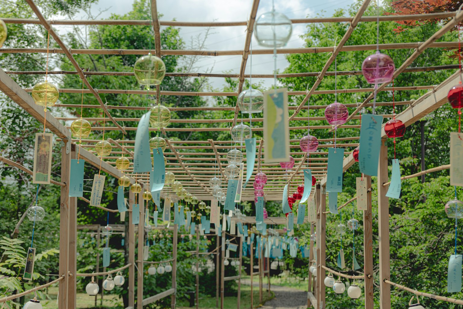 Ein hölzerner Bogen geschmückt mit bunten Windspielen und dekorativen Bändern