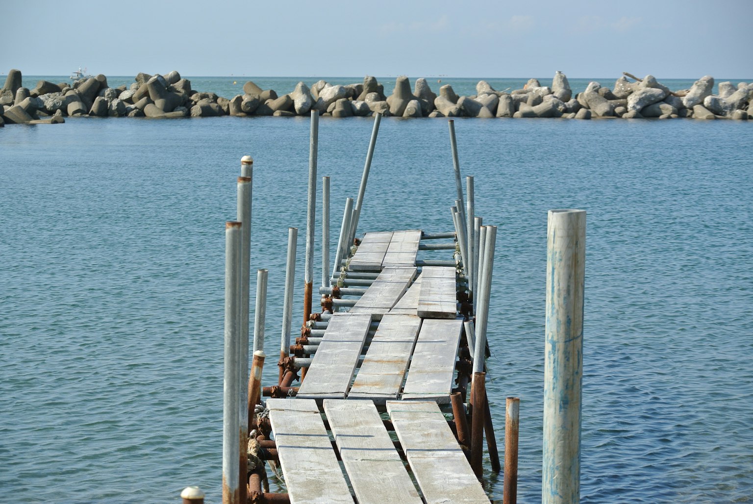 Quai en bois s'étendant dans une eau calme avec des rochers environnants