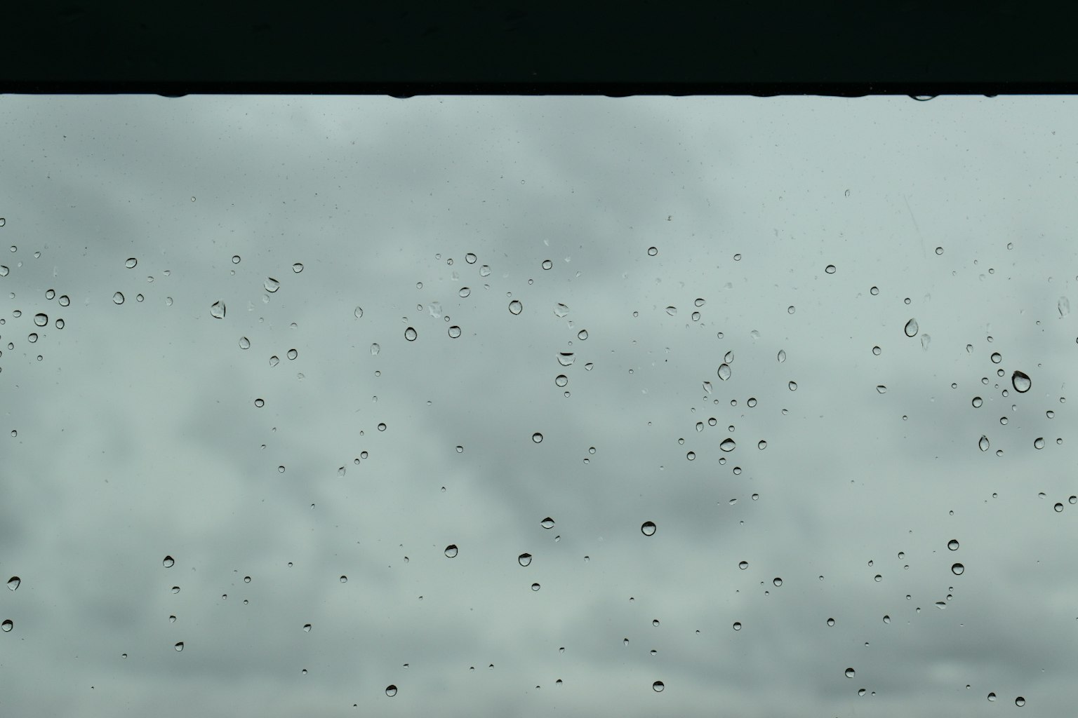 Gocce di pioggia su una finestra con cielo nuvoloso