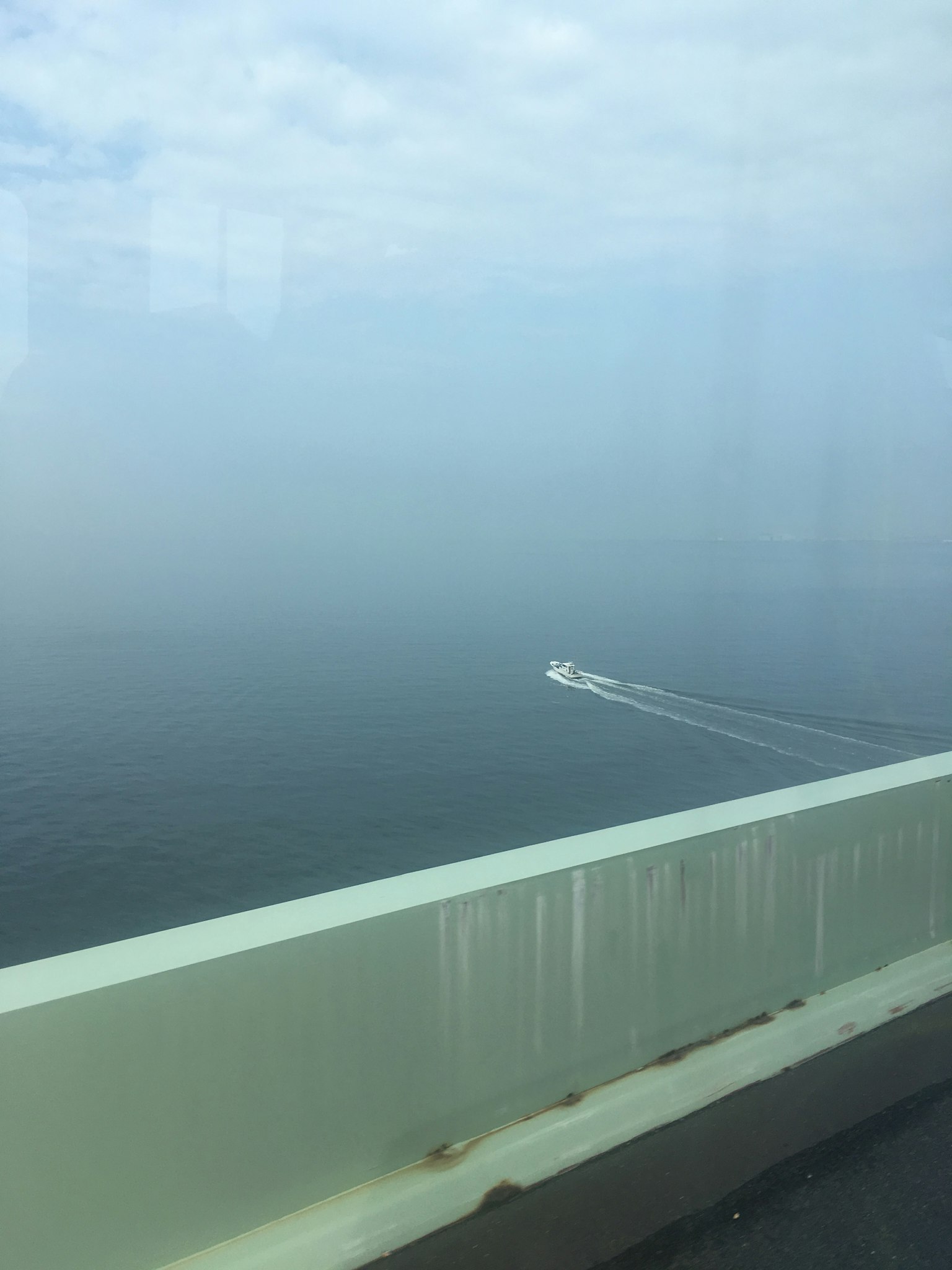 Boot, das auf einem nebligen Meer fährt, mit einem Teil einer Brücke im Blick