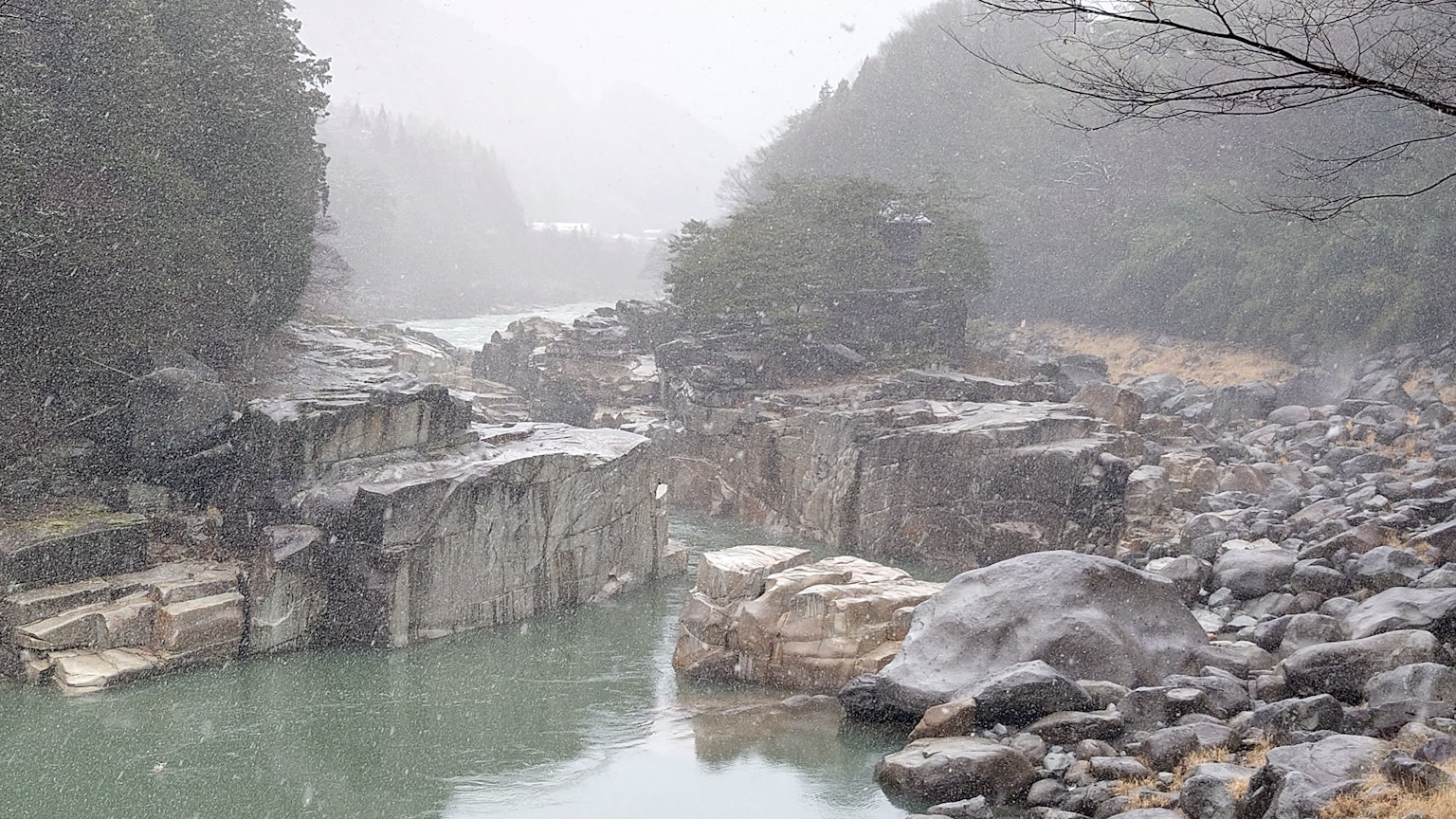 Verschneite Flusslandschaft mit Felsen und Nebel