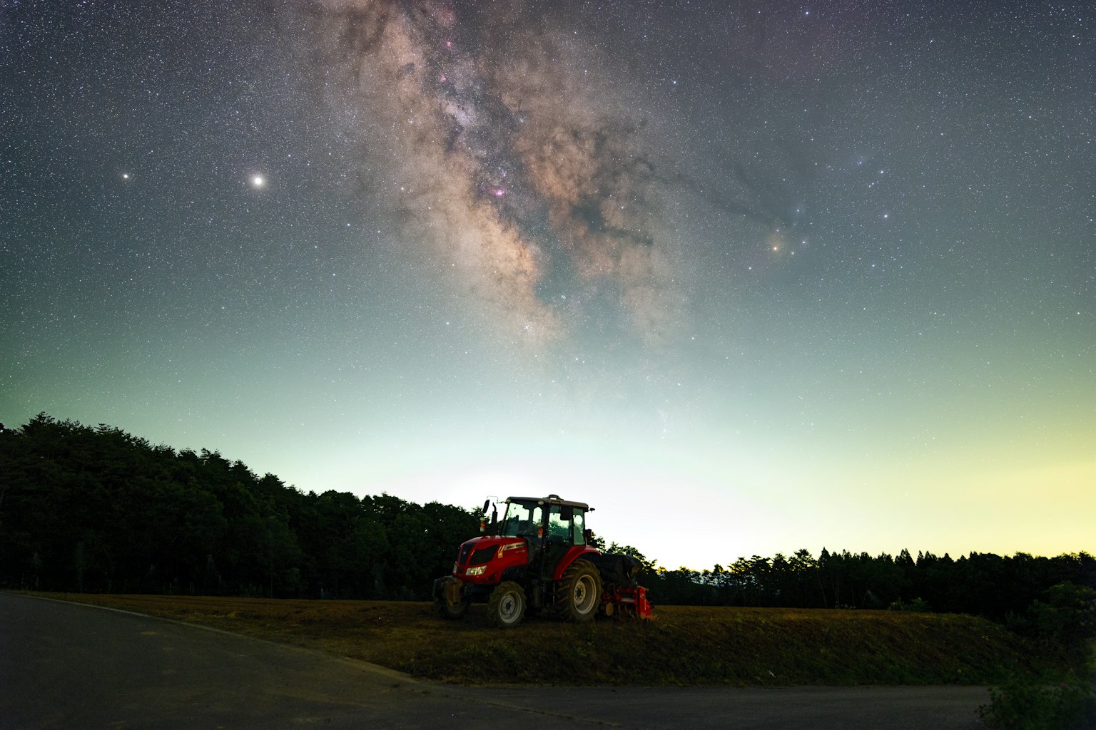 Silhouette of a red tractor against a starry Milky Way night sky