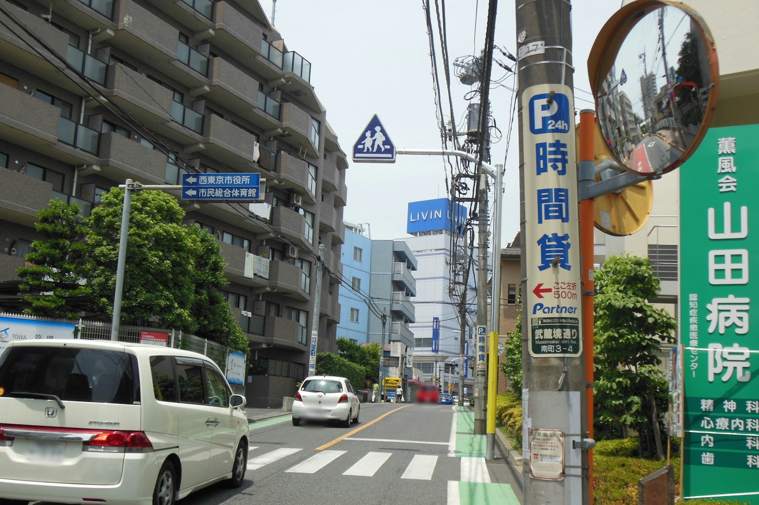 Residential street with white cars and signage visible