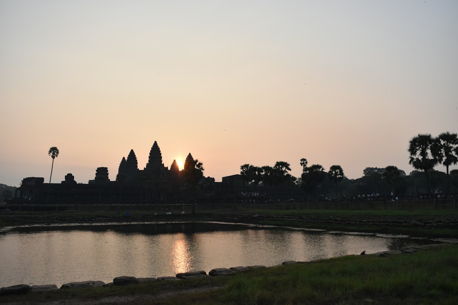 Silhouette of Angkor Wat with sunset reflection in water