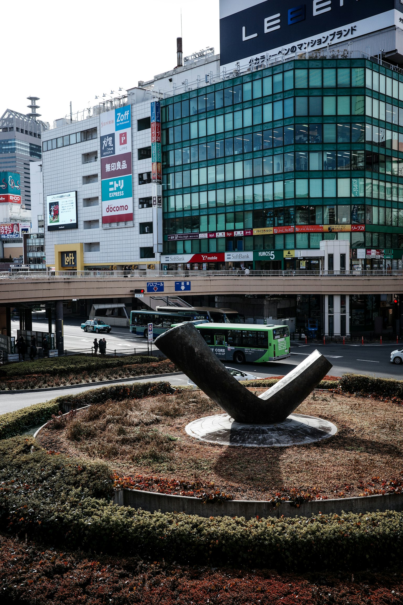 Escultura moderna frente a un edificio con vegetación