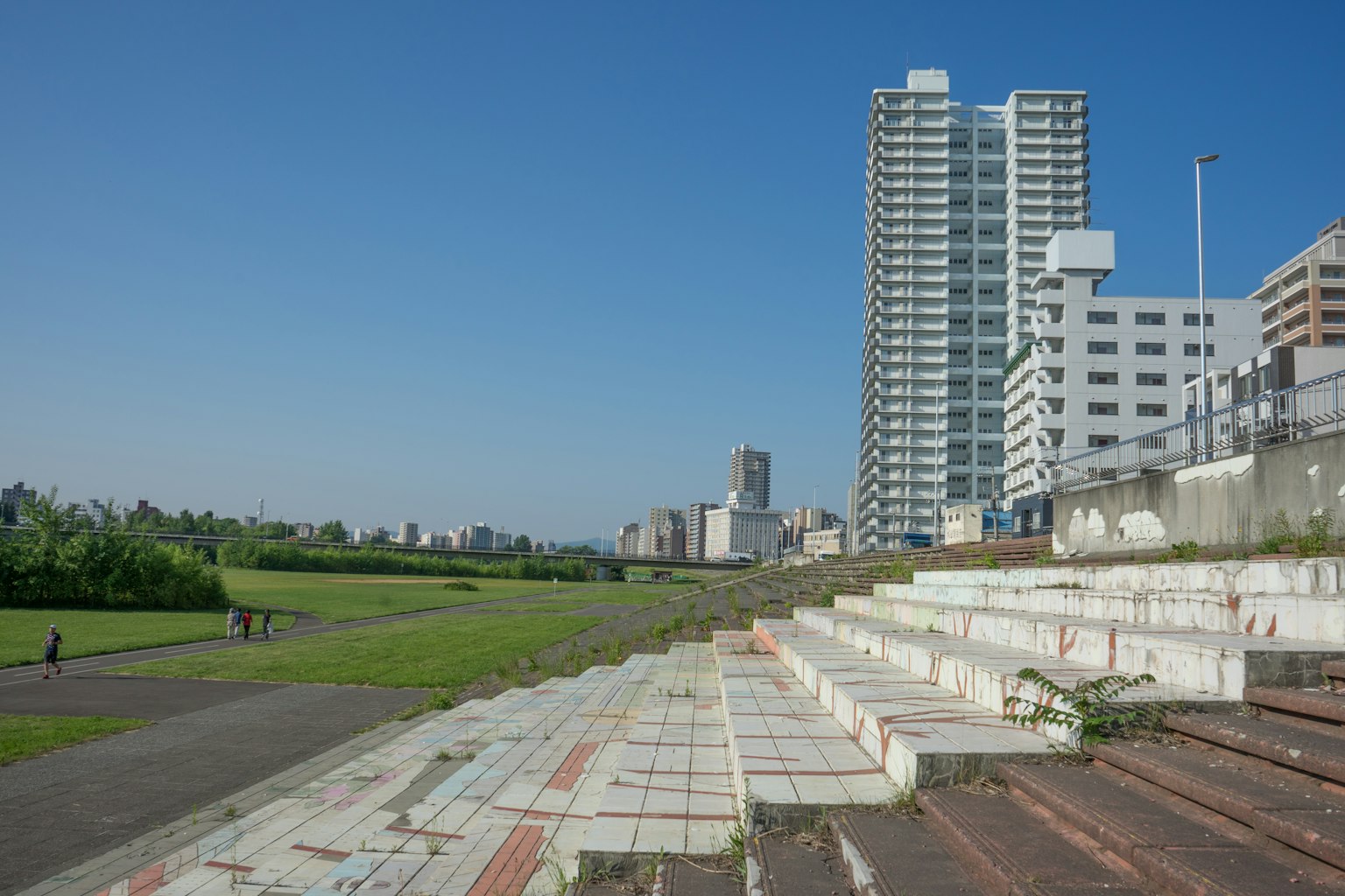 Paysage avec des immeubles de grande hauteur et un parc herbeux sous un ciel bleu