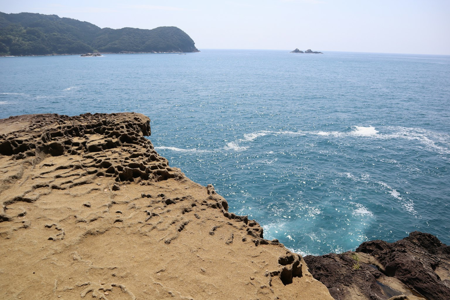 Blick auf den blauen Ozean von einer Felsenküste mit entfernten Inseln