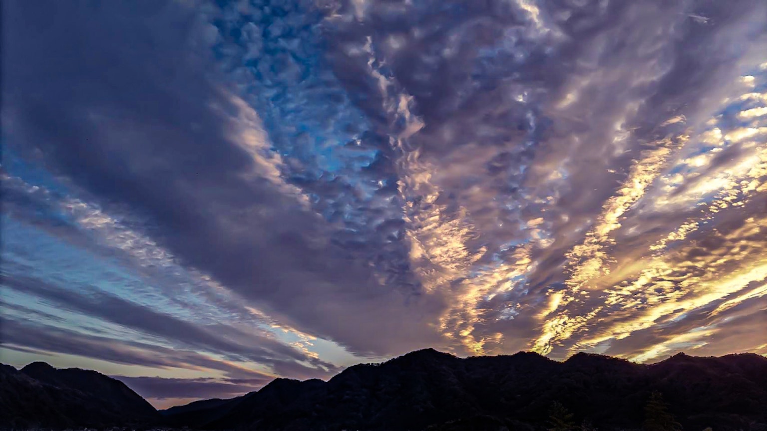 Paesaggio mozzafiato di montagne con nuvole colorate al tramonto