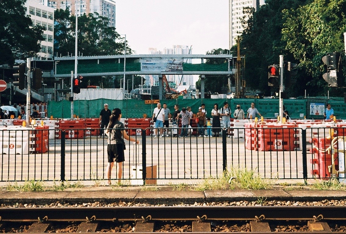 eingezäunte Bahngleise neben einer Baustelle in der Höhe und Stadtgebäuden