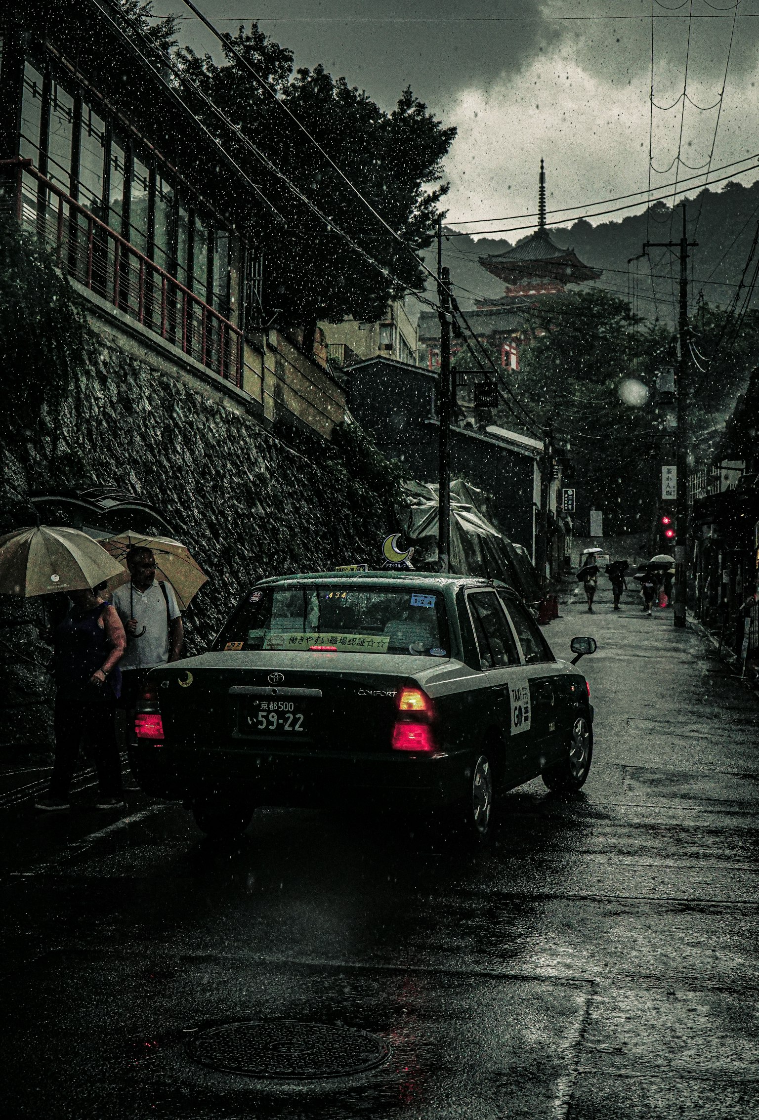 在雨中行驶的出租车与撑伞的人们
