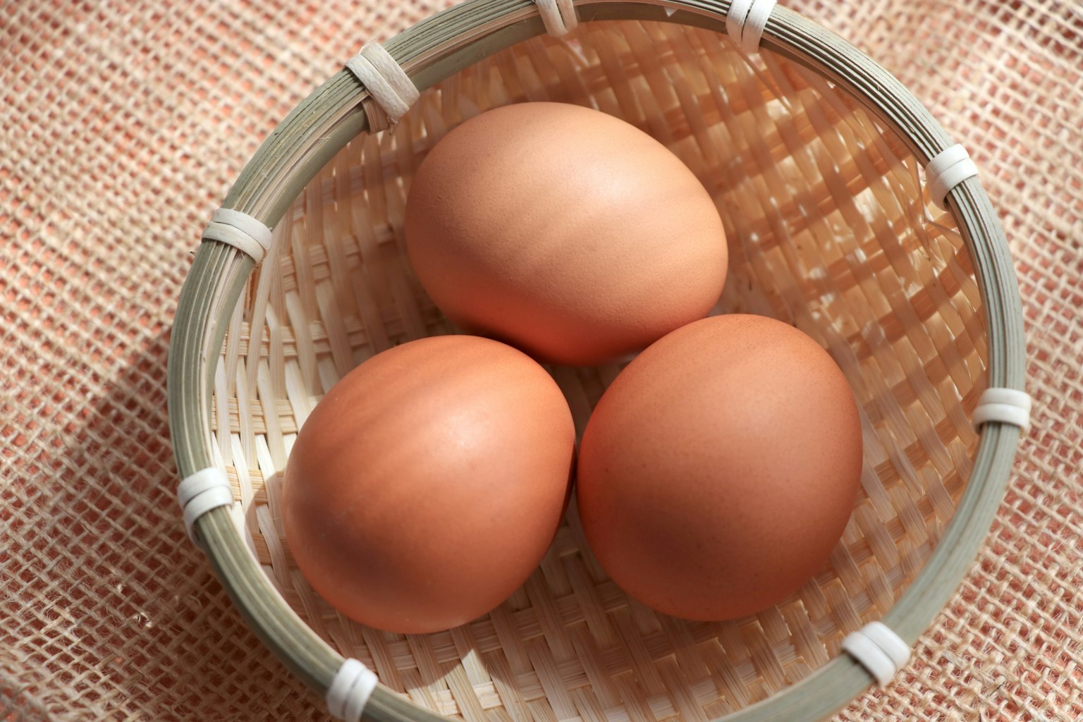 Three brown eggs in a woven basket