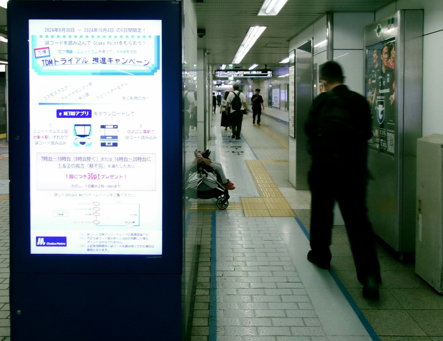 Scène d'une plateforme de gare avec des personnes et un panneau d'information