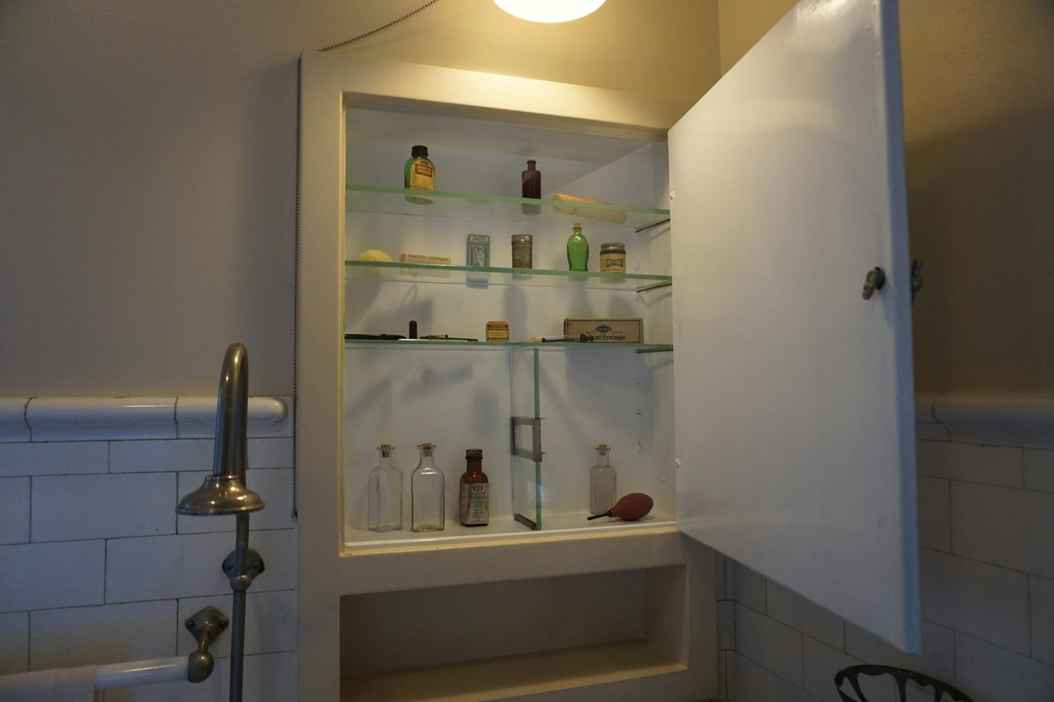 Armoire blanche avec des bouteilles en verre et des parfums exposés
