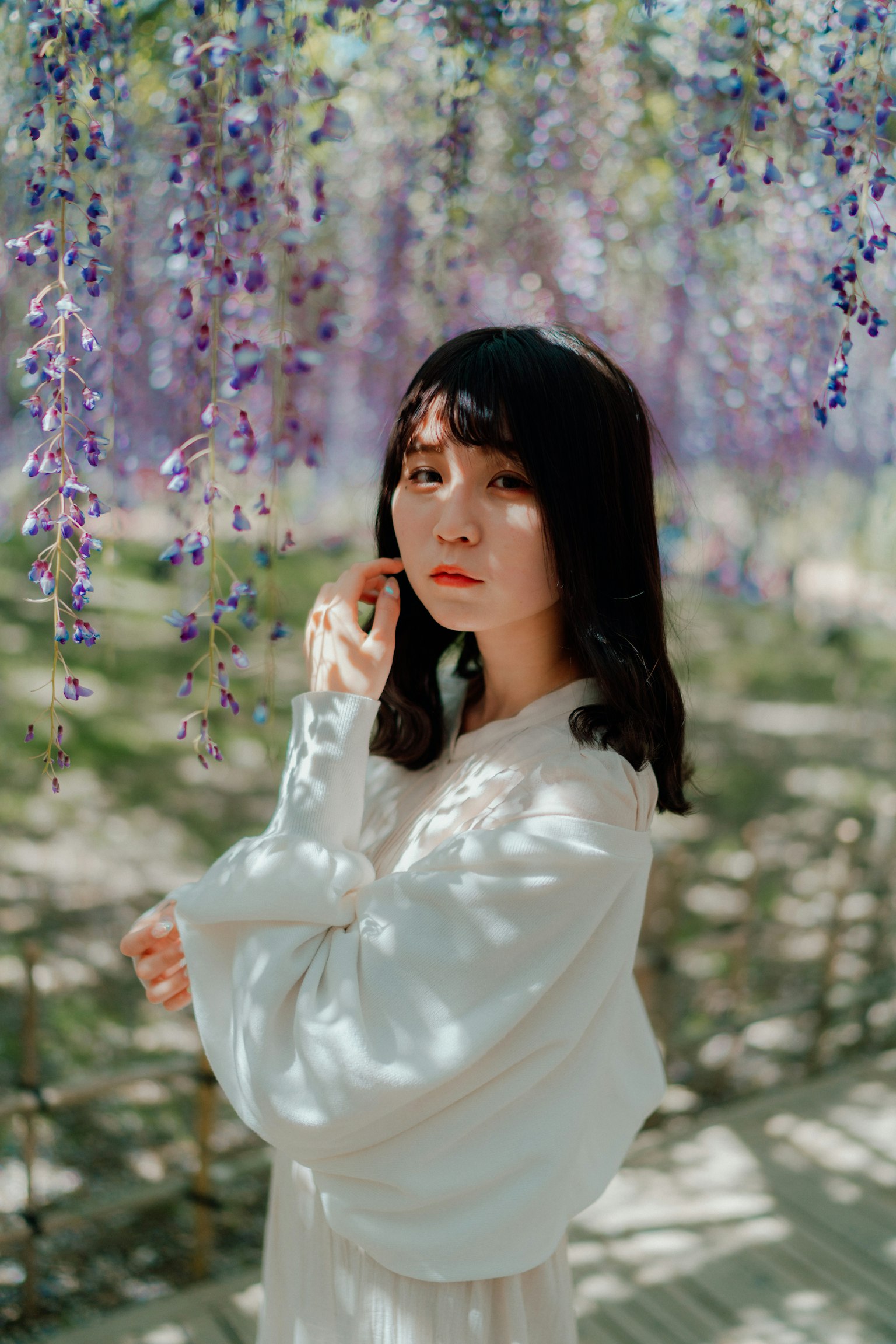 Woman posing under purple wisteria flowers