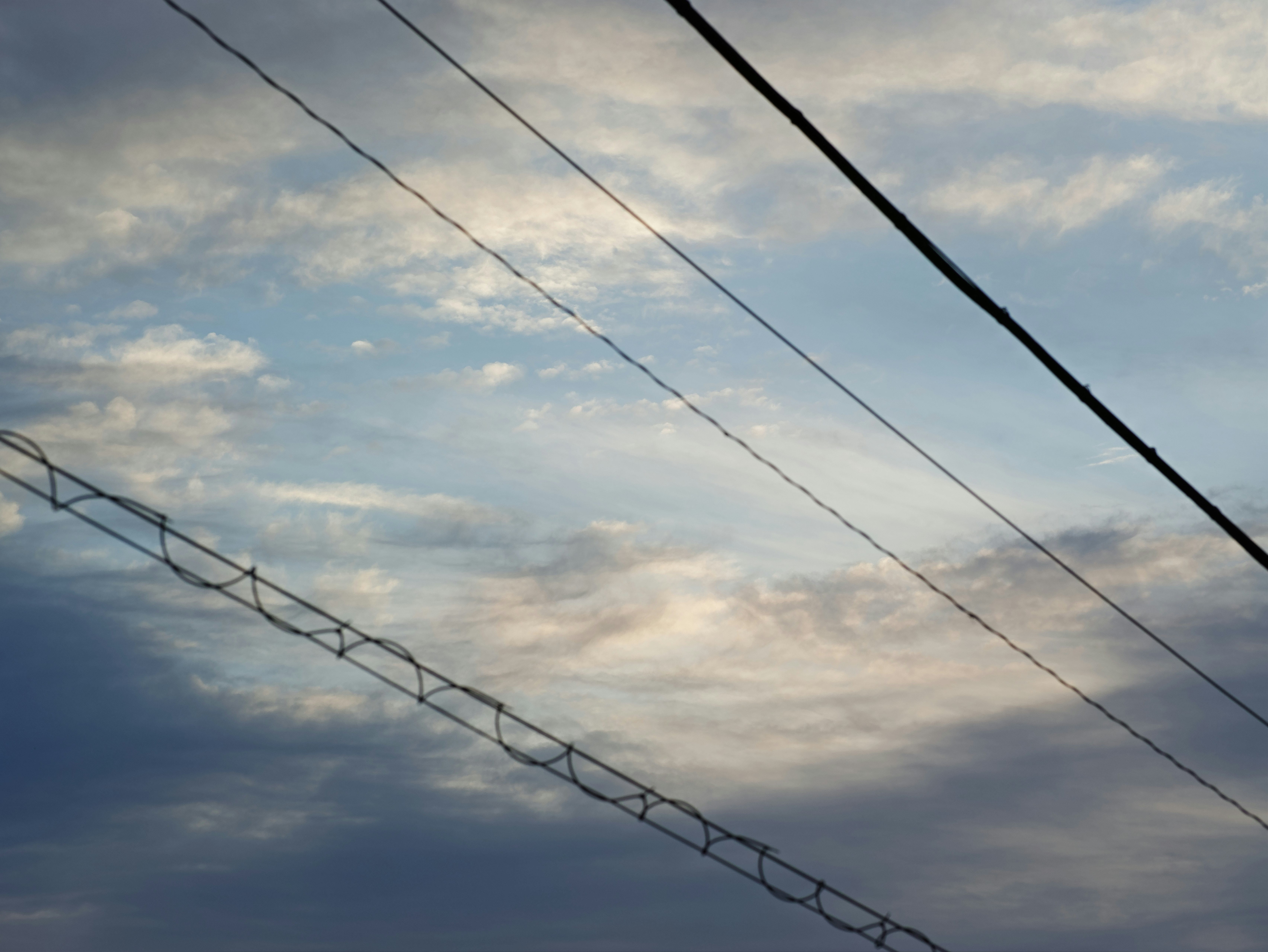 空に伸びる電線と雲の広がる空景