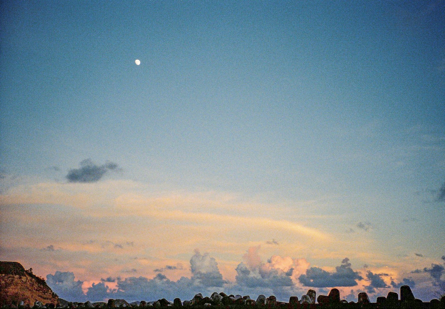 Pemandangan dengan langit biru, awan putih, dan bulan yang terlihat