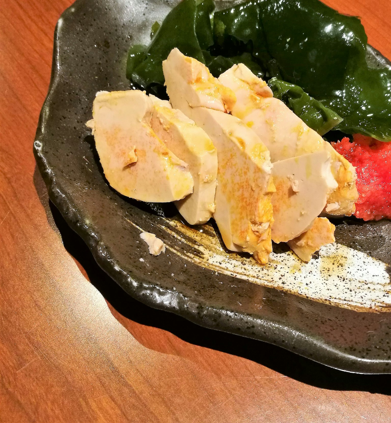 黑色盘子上的切片鸡肉和海藻沙拉