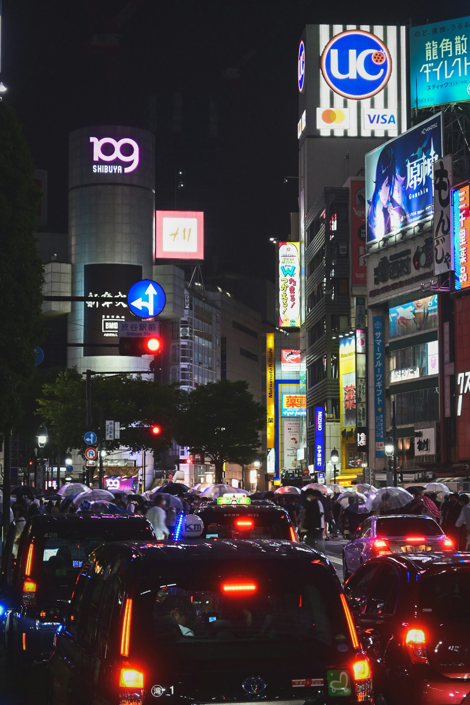 Pemandangan malam yang ramai di Shibuya Crossing dengan banyak mobil dan pejalan kaki