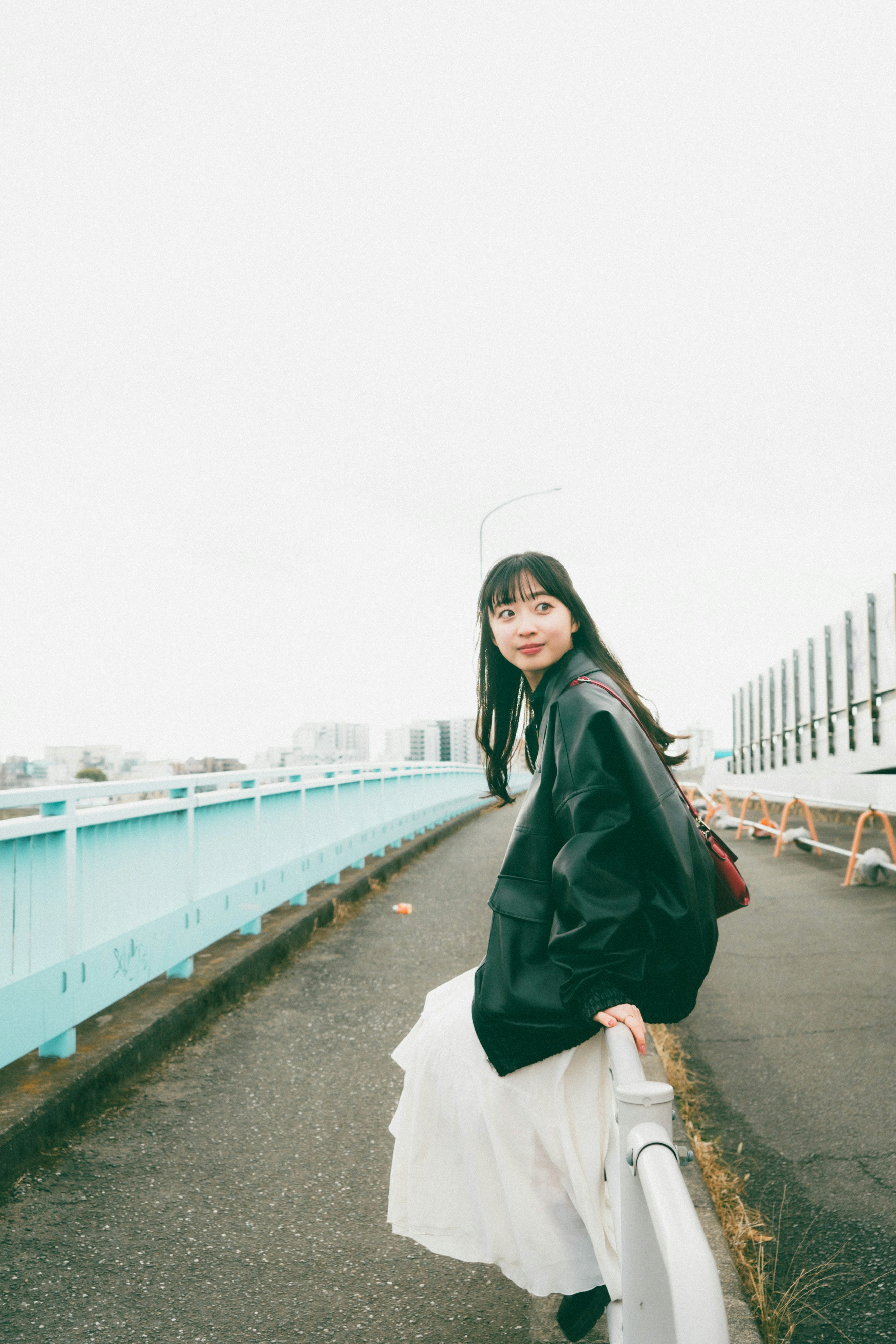 走在白色欄杆與藍色欄杆的海濱步道上的女性