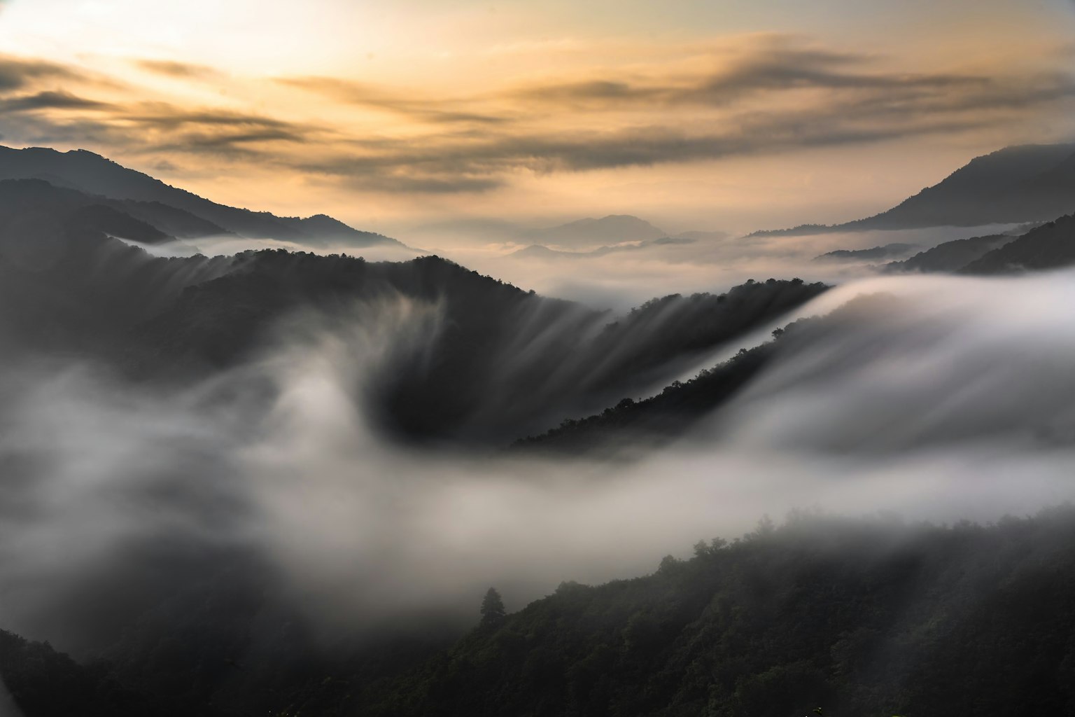 Montañas hermosas envueltas en niebla con un suave atardecer