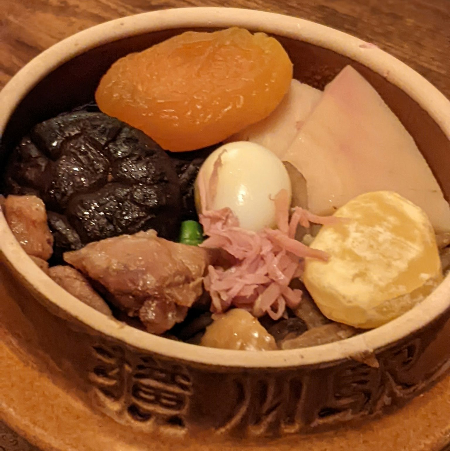 一个陶瓷碗装满各种食材包括香菇鸡肉鸡蛋和干果