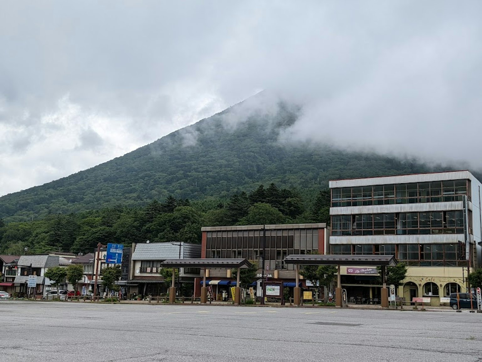 Vista di una montagna avvolta nella nebbia con edifici commerciali in primo piano