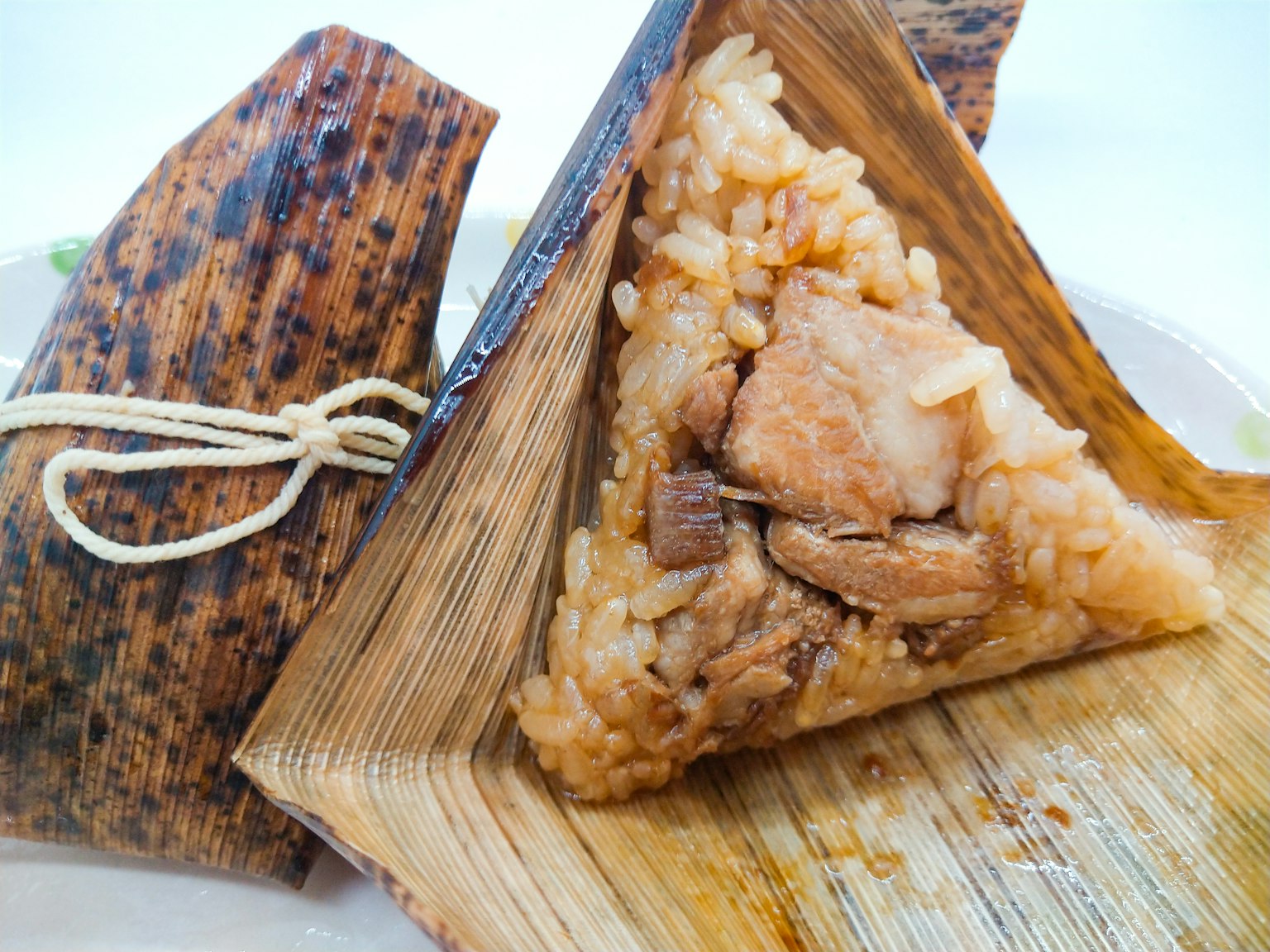 Hidangan nasi ketan segitiga dengan daging babi dibungkus daun pisang