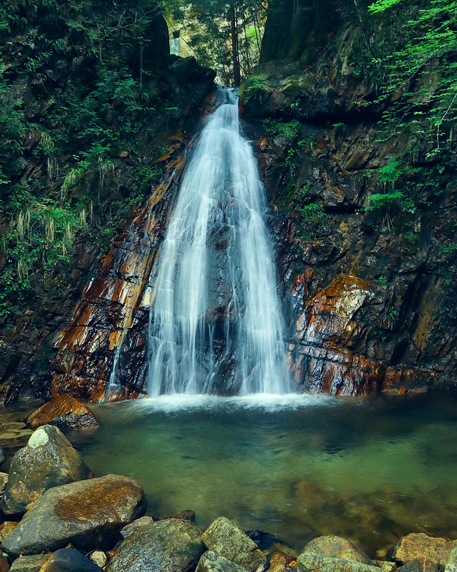 Ein beeindruckender Wasserfall, der über Felsen in einer üppigen grünen Umgebung fließt