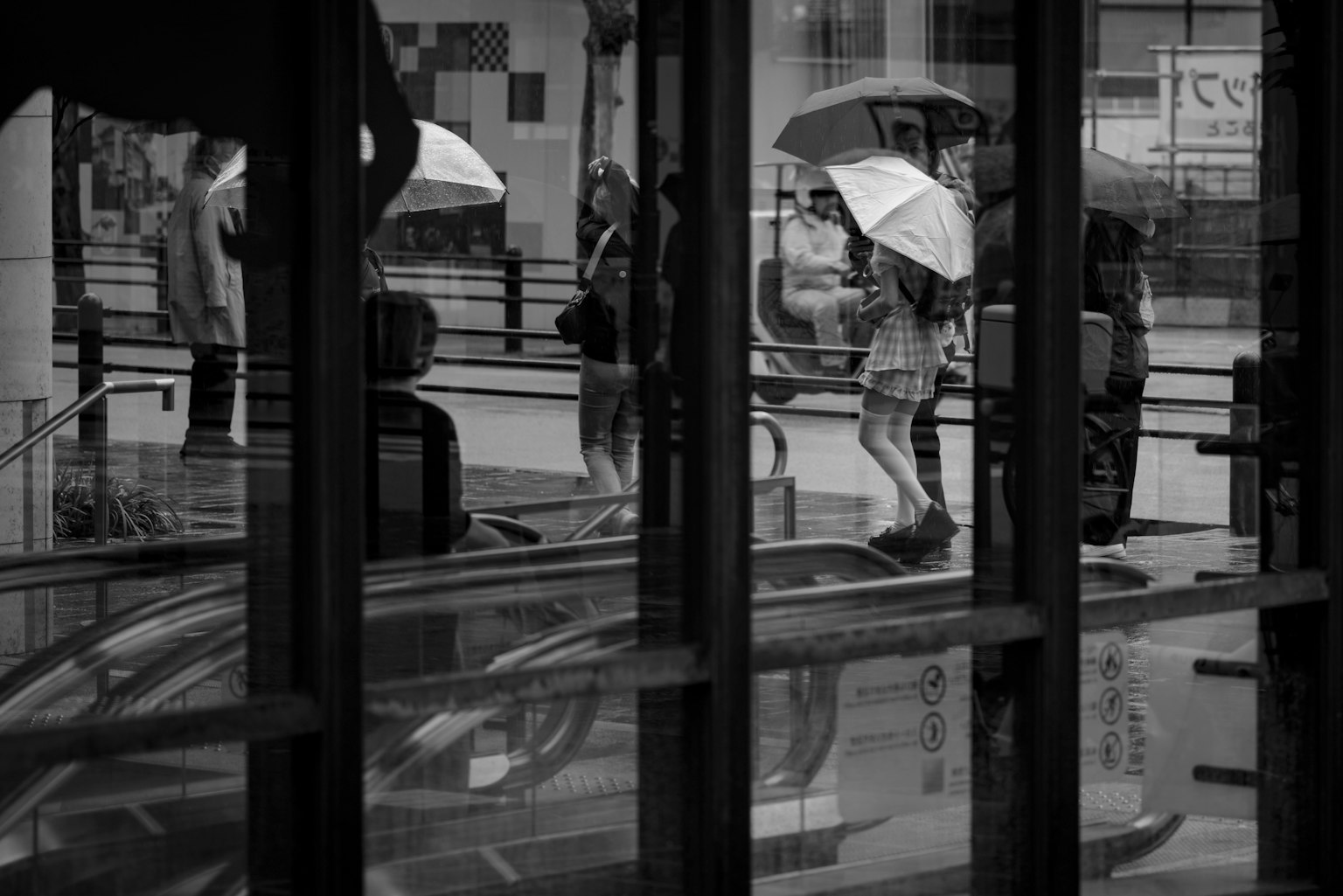 Black and white scene of people with umbrellas in the rain