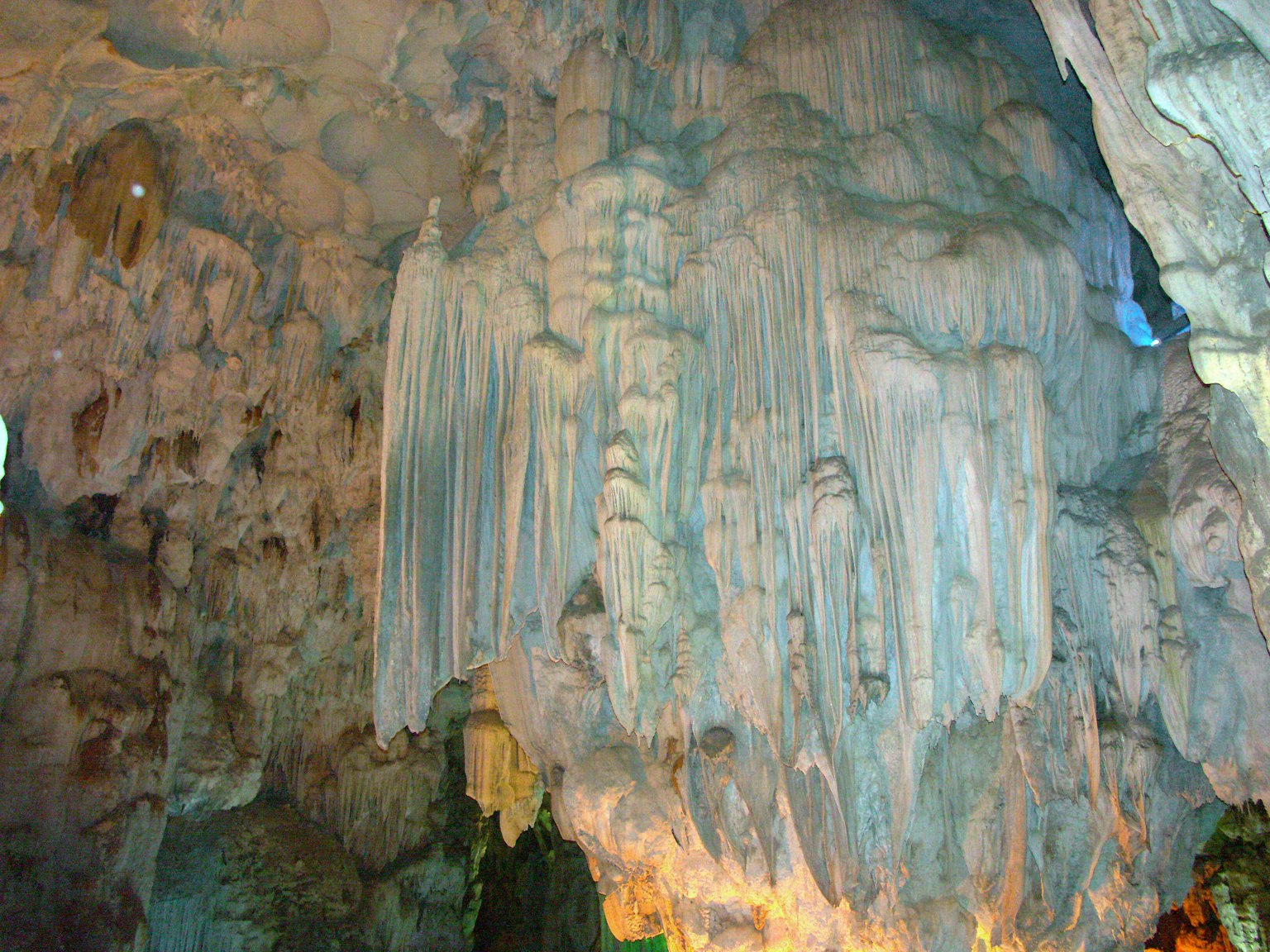 Stalaktiten in einer Kalksteinhöhle, beleuchtet von sanftem blauen Licht