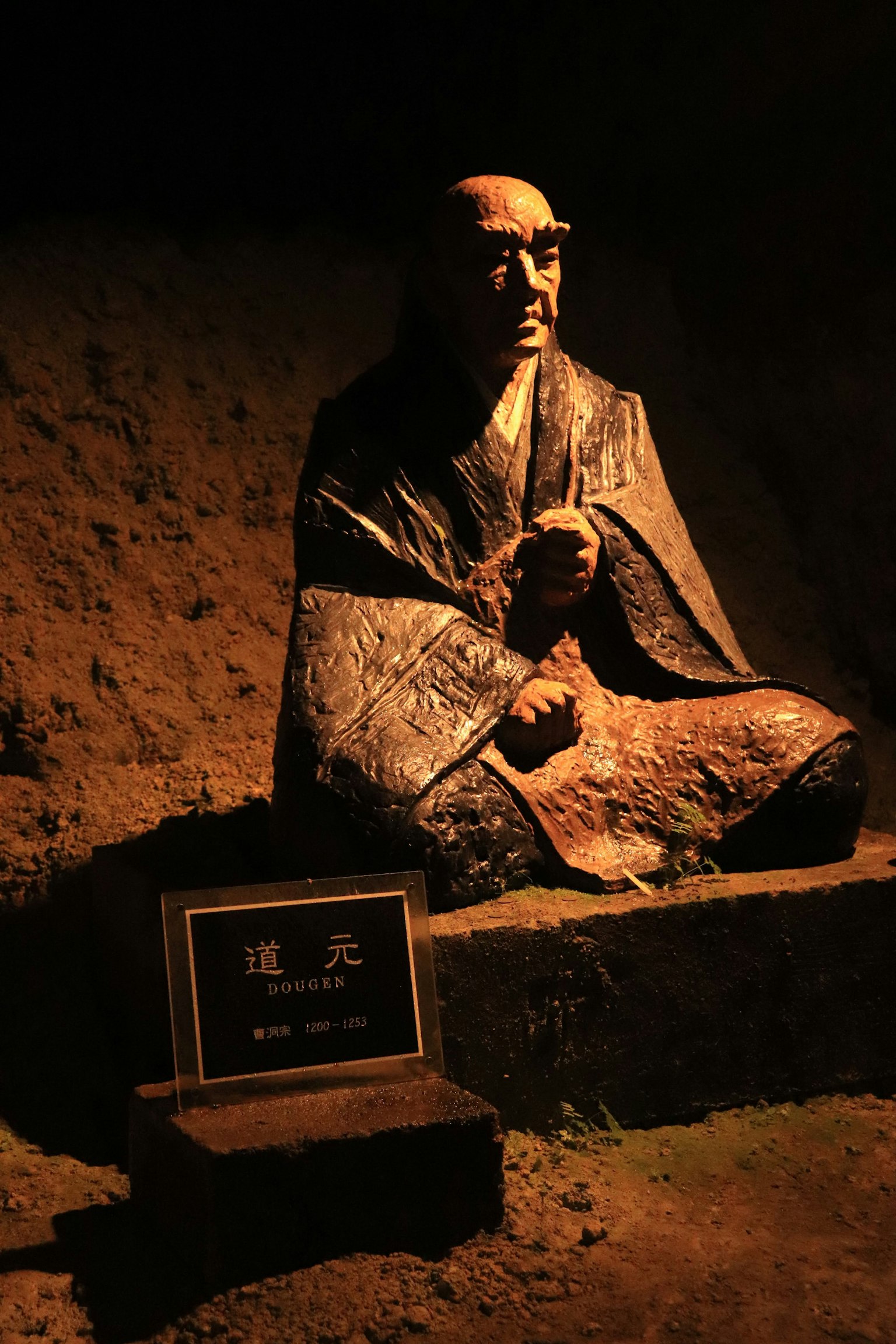 Une statue assise d'un moine dans un environnement faiblement éclairé