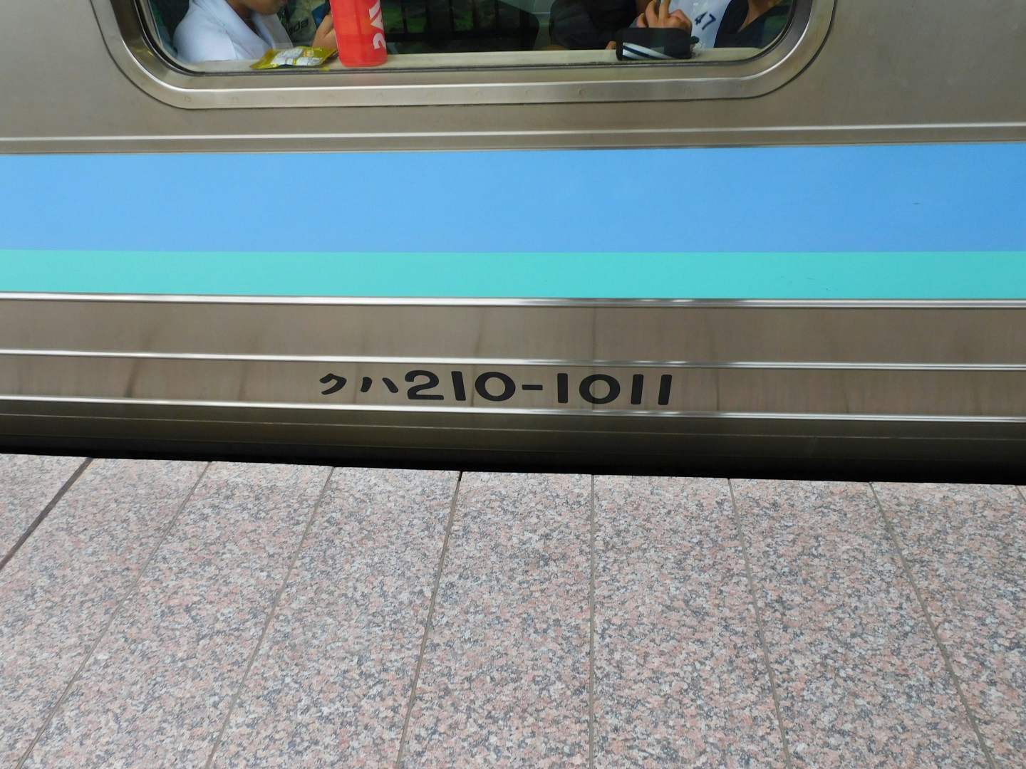 มองผ่านหน้าต่างรถไฟเห็นพื้นชานชาลาและด้านข้างตู้โดยสาร