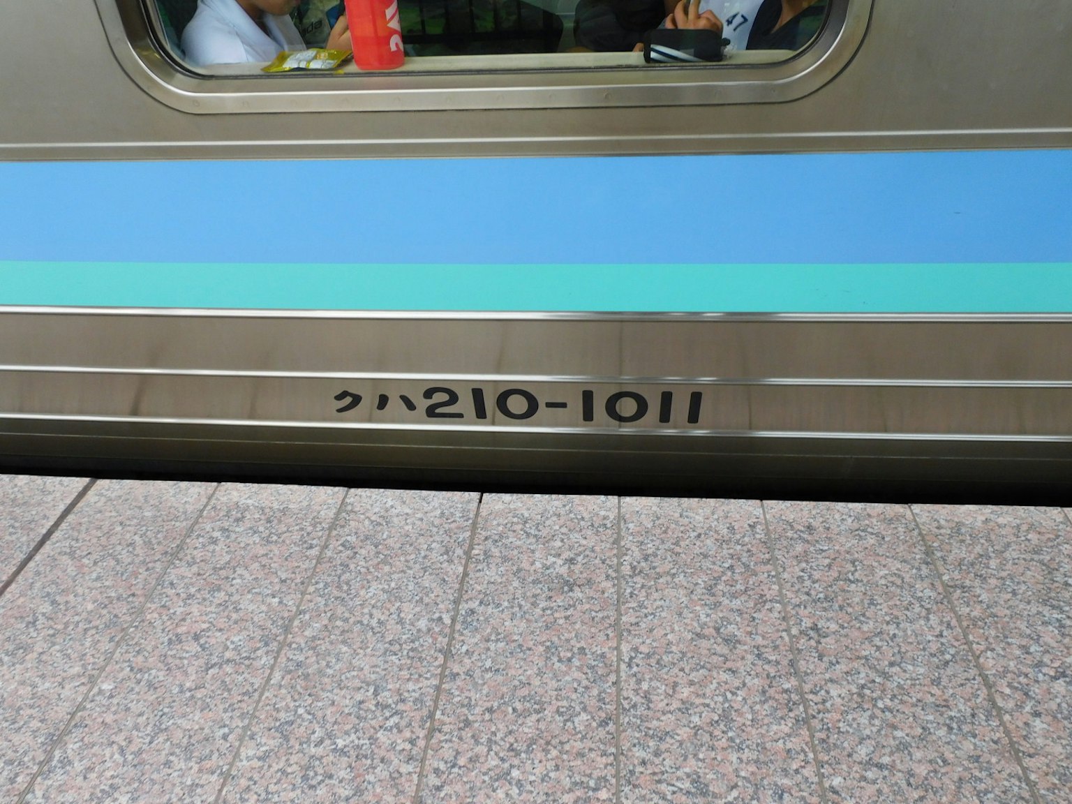 Tampilan samping kereta dengan garis biru dan nomor 210-1011
