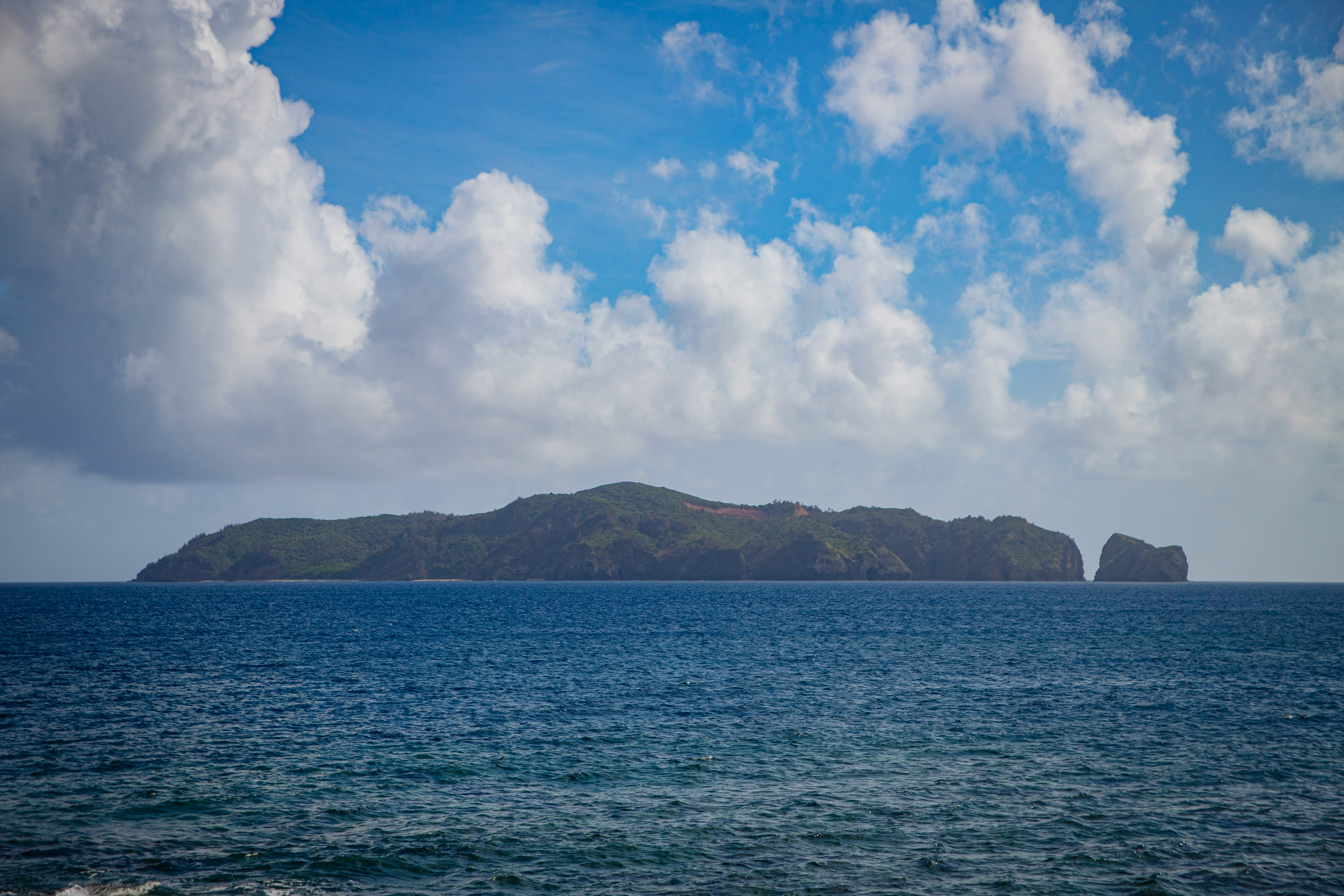 青い海と水平線、島と岩が見える海景の画像