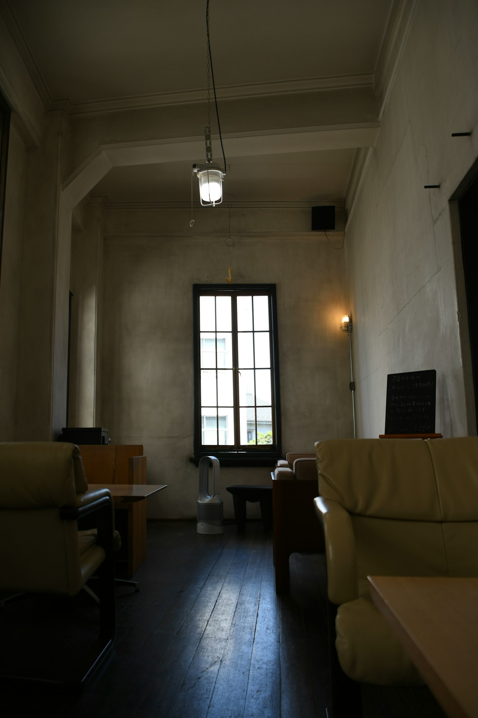 Une pièce simple avec des murs blancs et un sol noir avec une grande fenêtre et des canapés