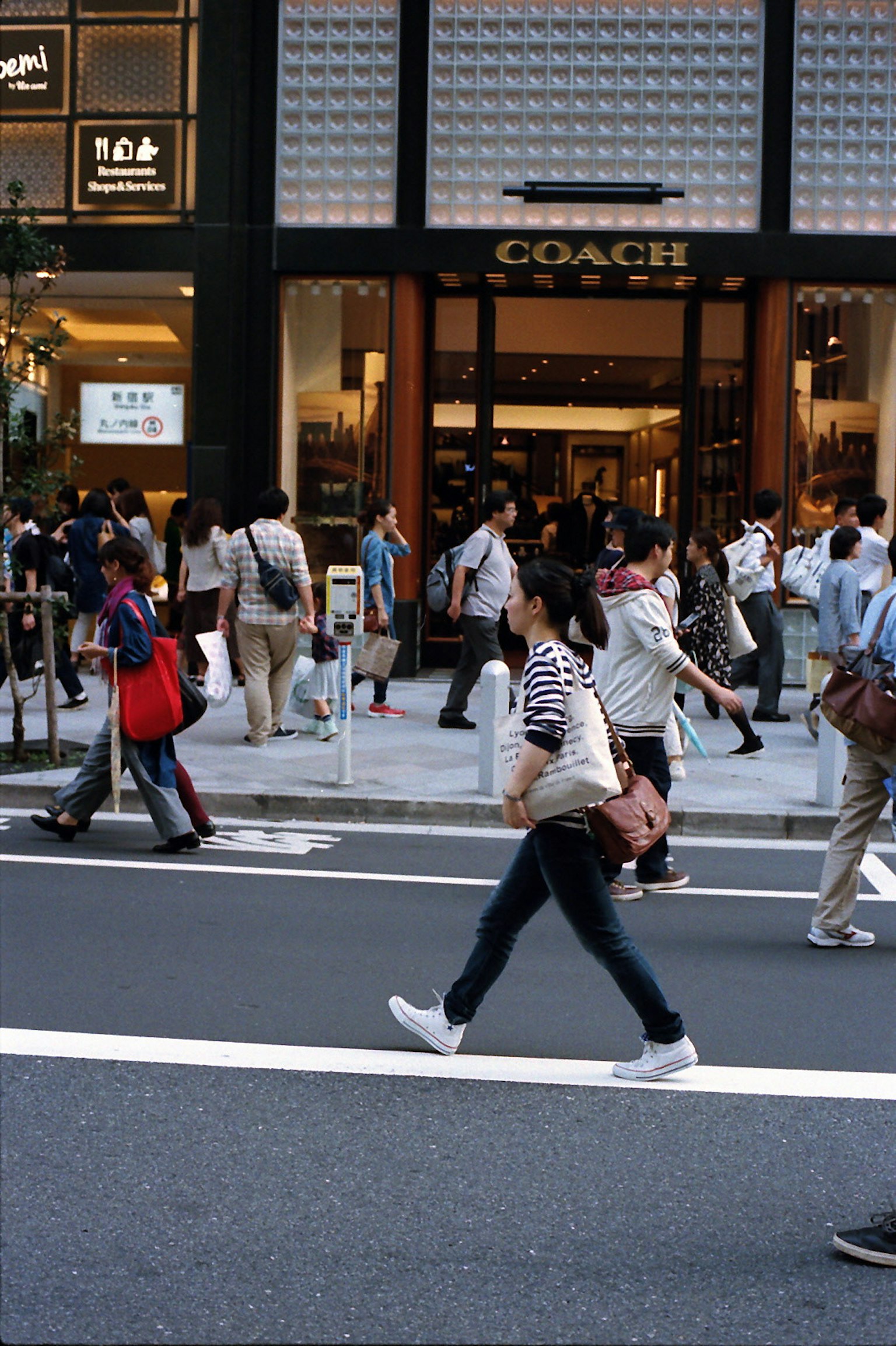 Busy street scene with people walking past a Coach store
