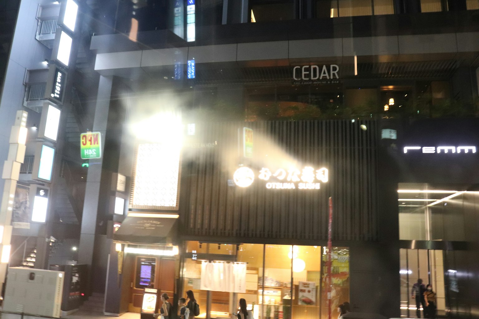 Pemandangan kota malam hari dengan eksterior CEDAR yang diterangi dan asap