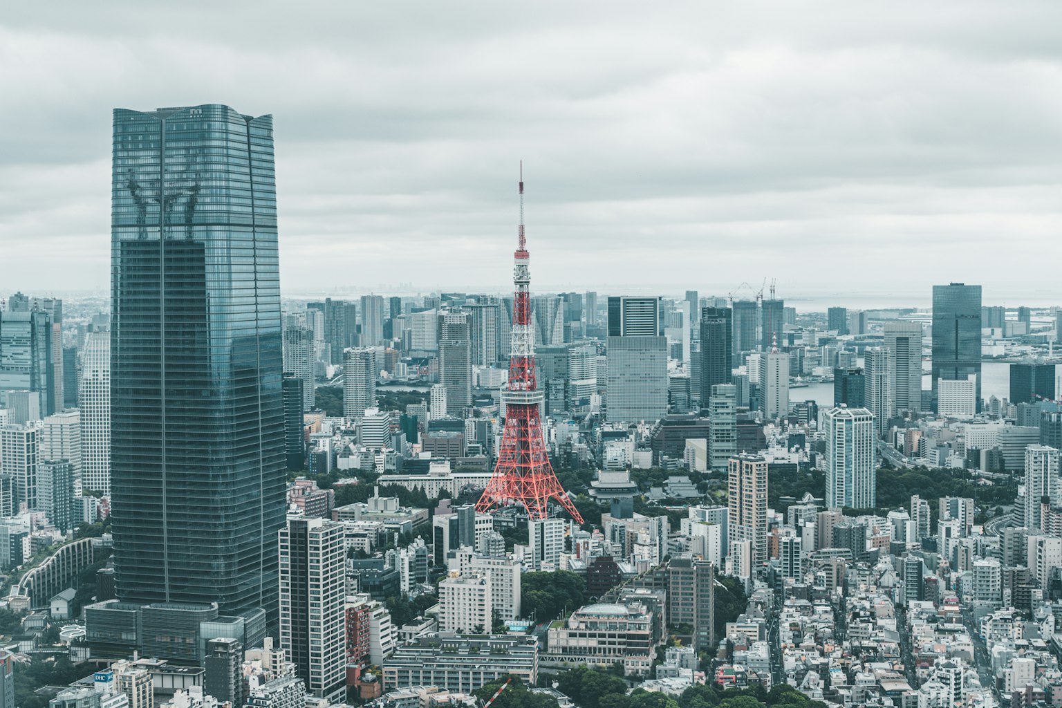 ทิวทัศน์เมืองที่มีโตเกียวทาวเวอร์ตั้งอยู่ท่ามกลางตึกสูงและท้องฟ้าสีเทา
