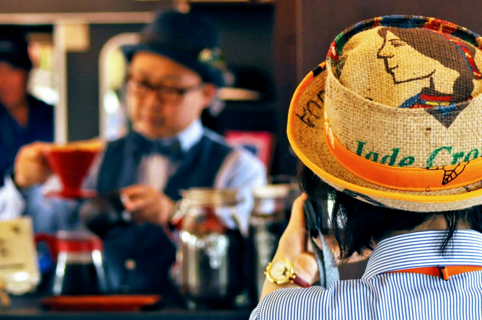 Un homme versant du café dans un café avec une femme portant un chapeau